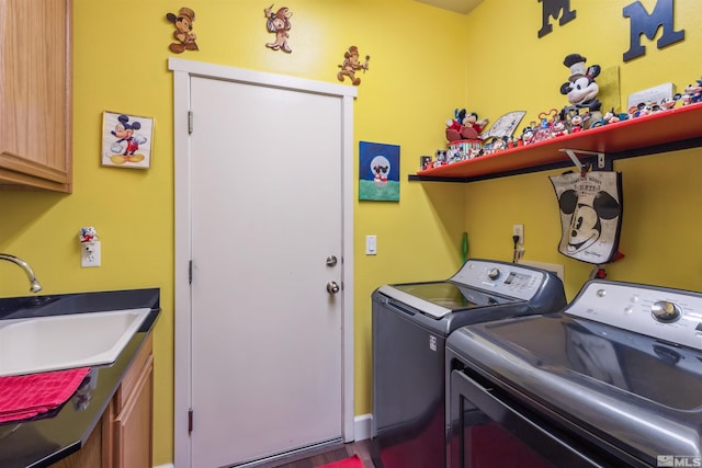 clothes washing area with cabinets, washer and clothes dryer, and sink