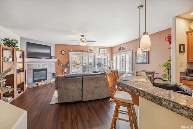 living room featuring sink, a fireplace, ceiling fan, and dark hardwood / wood-style floors