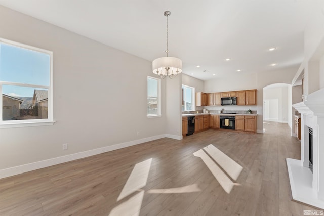 kitchen featuring decorative light fixtures, an inviting chandelier, light wood-type flooring, and black appliances