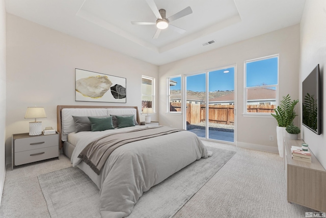 carpeted bedroom featuring access to outside, ceiling fan, and a tray ceiling