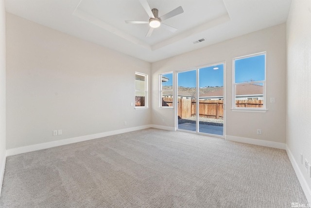 spare room with ceiling fan, light colored carpet, and a raised ceiling