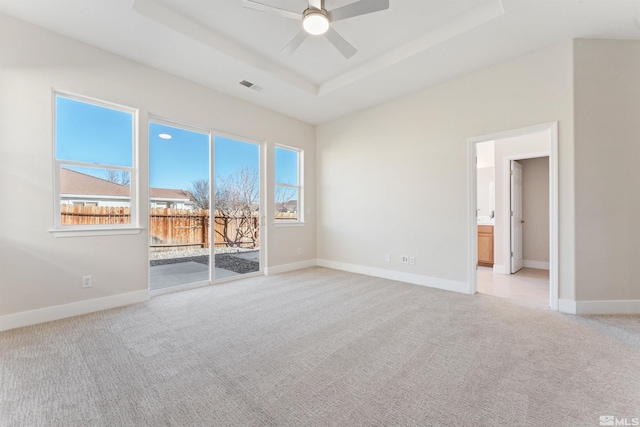 carpeted empty room featuring a raised ceiling and ceiling fan