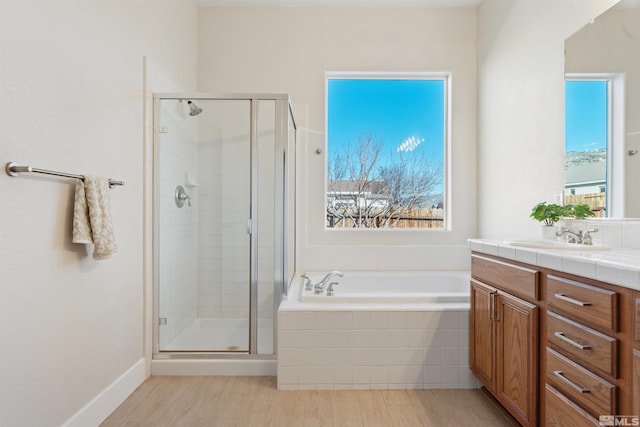 bathroom featuring independent shower and bath, vanity, and a healthy amount of sunlight