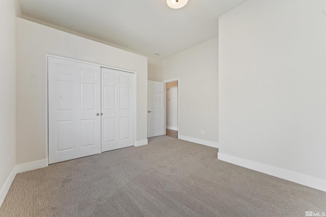 unfurnished bedroom with light colored carpet and a closet