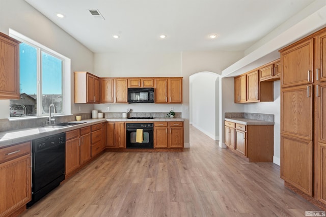 kitchen with black appliances, light wood-type flooring, and sink