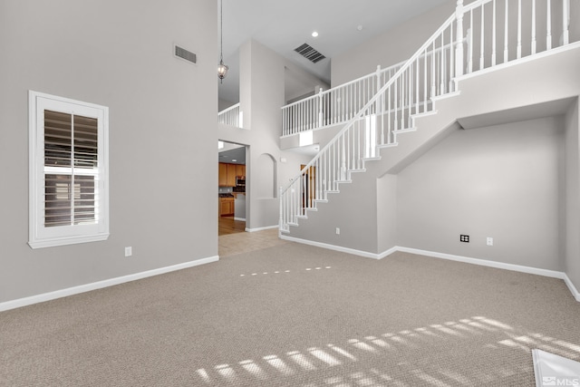 unfurnished living room with a high ceiling and carpet floors