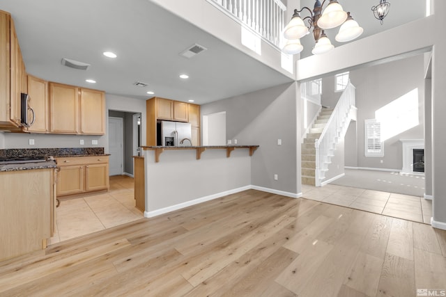 kitchen with pendant lighting, stainless steel appliances, a notable chandelier, light wood-type flooring, and a kitchen breakfast bar