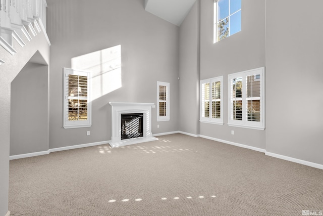 unfurnished living room with a towering ceiling and carpet floors