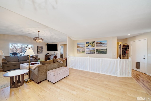 living room with vaulted ceiling, light hardwood / wood-style floors, and a chandelier