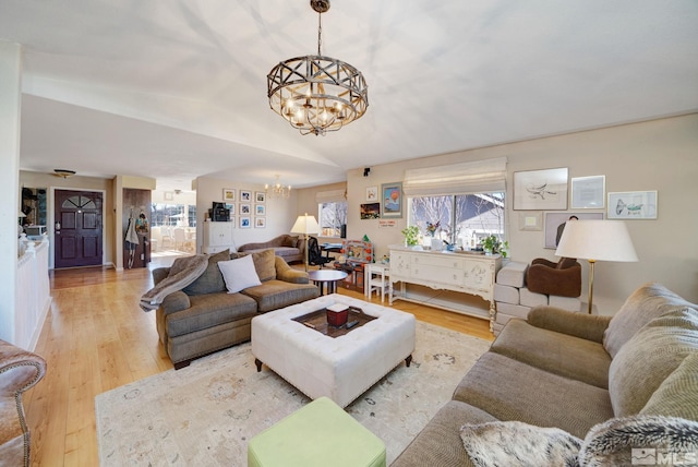 living room with lofted ceiling, light wood-type flooring, and a notable chandelier