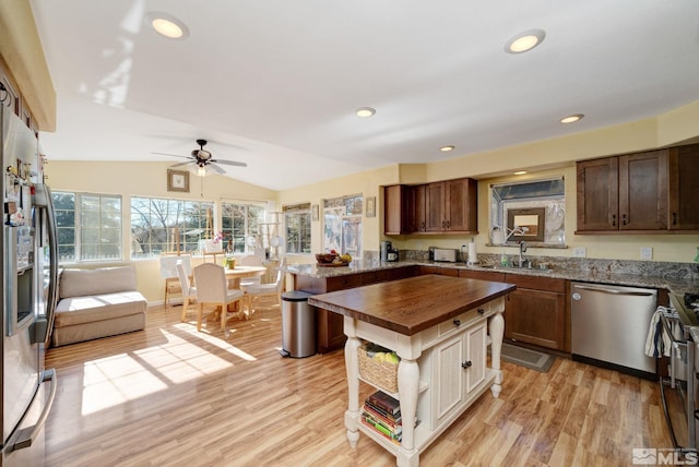 kitchen featuring butcher block counters, lofted ceiling, light wood-type flooring, appliances with stainless steel finishes, and sink