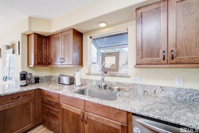 kitchen with sink, stainless steel dishwasher, and light stone countertops