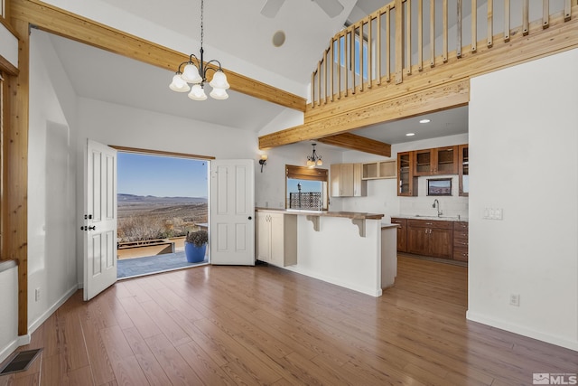 kitchen with pendant lighting, dark hardwood / wood-style floors, a breakfast bar, beam ceiling, and sink