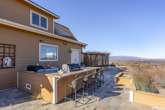 view of patio / terrace with grilling area, exterior bar, a mountain view, and area for grilling