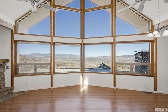 unfurnished sunroom with ceiling fan with notable chandelier, vaulted ceiling, and a mountain view