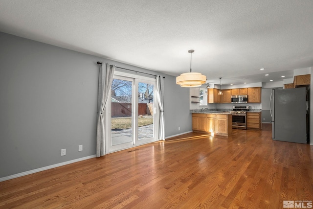 kitchen featuring a textured ceiling, hardwood / wood-style flooring, stainless steel appliances, and pendant lighting