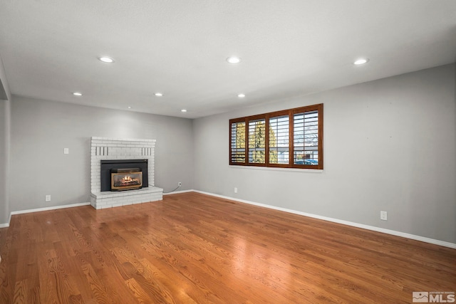 unfurnished living room with a brick fireplace and hardwood / wood-style floors