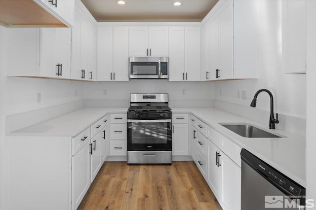 kitchen featuring sink, stainless steel appliances, light hardwood / wood-style floors, and white cabinets