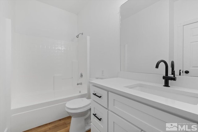 full bathroom with hardwood / wood-style floors, toilet, vanity, and shower / bath combination