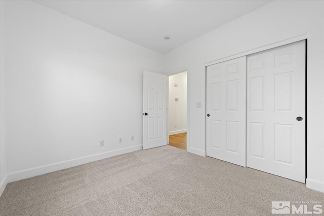 unfurnished bedroom featuring a closet and light carpet