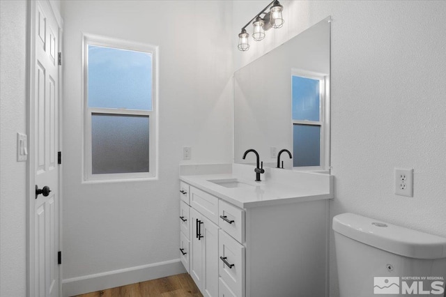 bathroom with toilet, vanity, and hardwood / wood-style floors