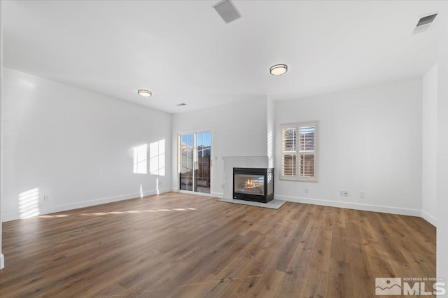 unfurnished living room with hardwood / wood-style floors and a multi sided fireplace