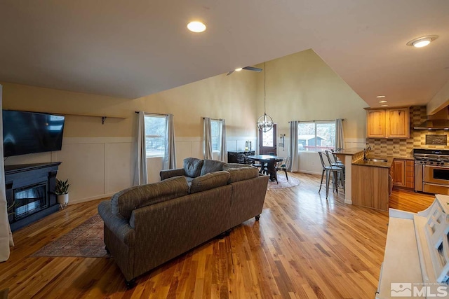 living room with sink, light wood-type flooring, and vaulted ceiling