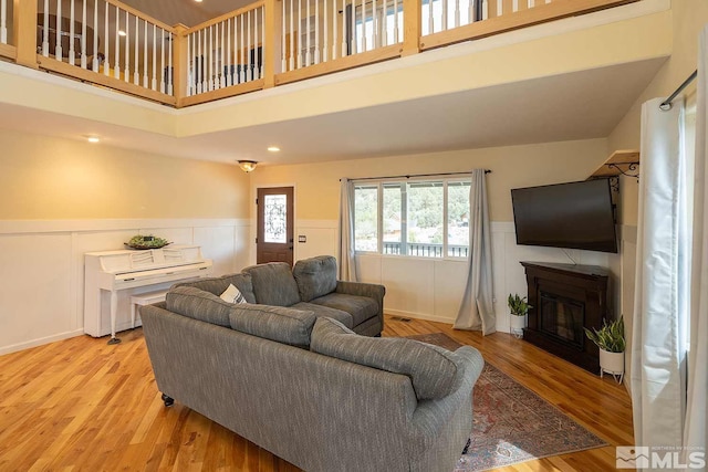 living room featuring a towering ceiling and light wood-type flooring