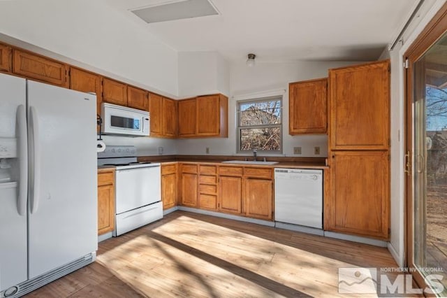 kitchen with sink, white appliances, lofted ceiling, and light hardwood / wood-style flooring