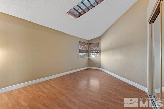 spare room featuring lofted ceiling, a textured ceiling, and hardwood / wood-style flooring