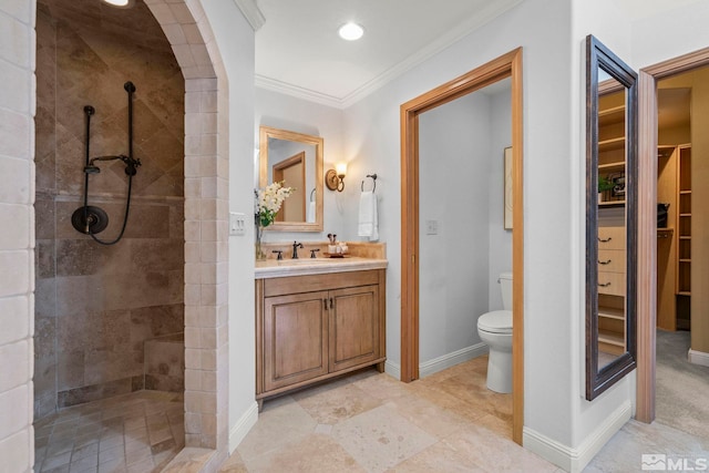 bathroom featuring toilet, crown molding, tiled shower, and vanity