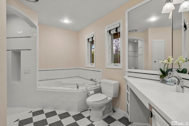 bathroom featuring toilet, a relaxing tiled tub, and vanity