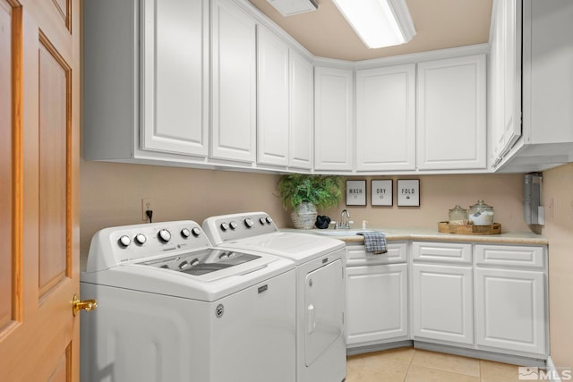 laundry area with washing machine and clothes dryer, light tile patterned floors, and cabinets