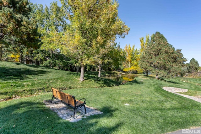 view of property's community with a lawn and a water view