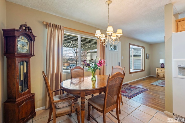 dining room with a notable chandelier, light tile patterned flooring, and a textured ceiling