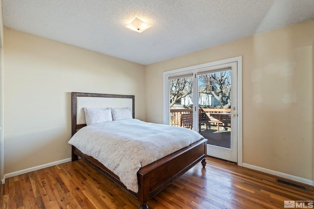 bedroom with a textured ceiling, dark hardwood / wood-style floors, and access to exterior