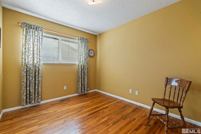 empty room with a textured ceiling and hardwood / wood-style floors