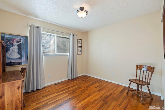 interior space with a textured ceiling and hardwood / wood-style floors