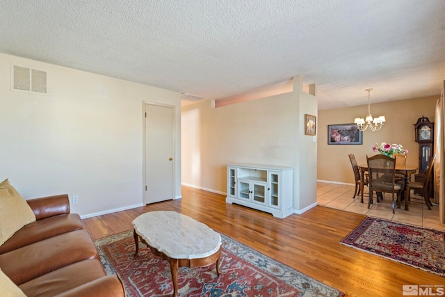 living room featuring a notable chandelier, light hardwood / wood-style floors, and a textured ceiling