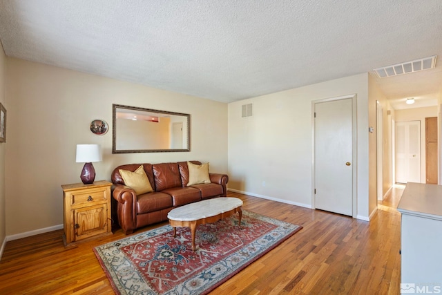 living room with a textured ceiling and light hardwood / wood-style flooring