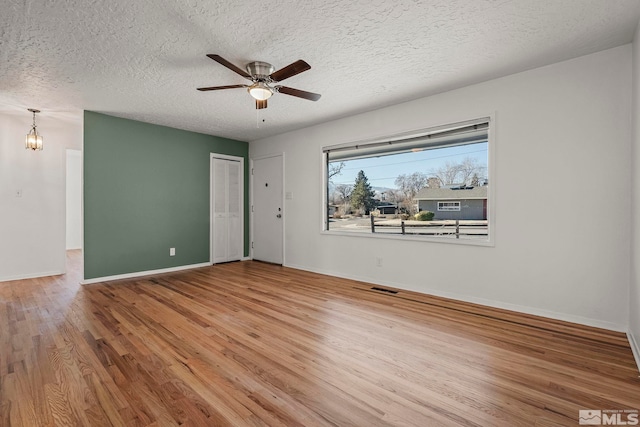 spare room featuring a textured ceiling, ceiling fan with notable chandelier, and wood-type flooring