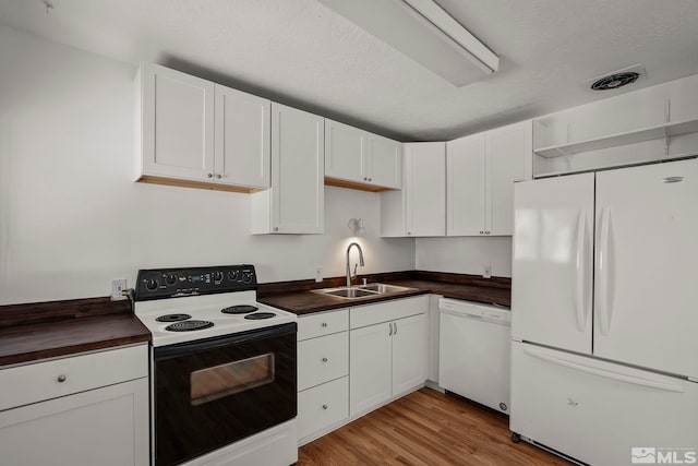 kitchen with white appliances, a textured ceiling, light wood-type flooring, white cabinets, and sink