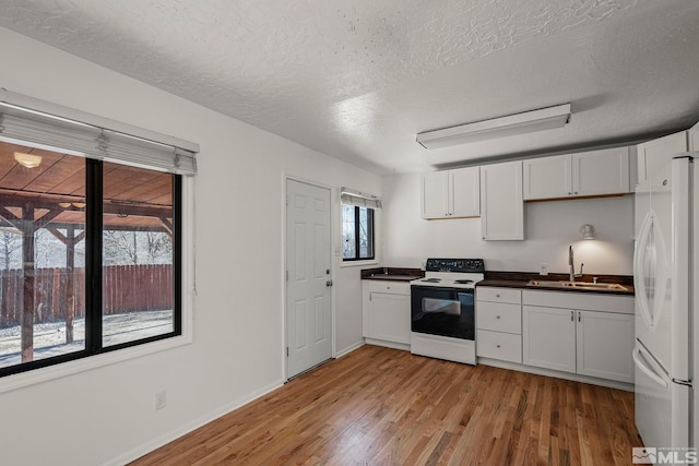 kitchen with electric range oven, white cabinets, sink, and white fridge