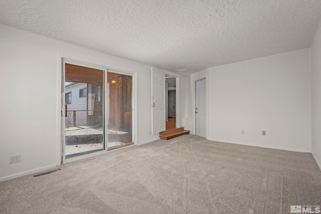 carpeted empty room with a textured ceiling