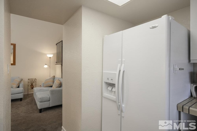 interior space with white refrigerator with ice dispenser and dark carpet