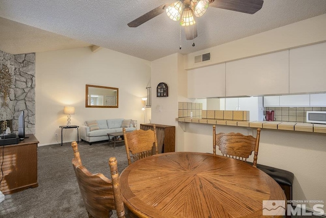 carpeted dining space featuring a textured ceiling, beam ceiling, and ceiling fan