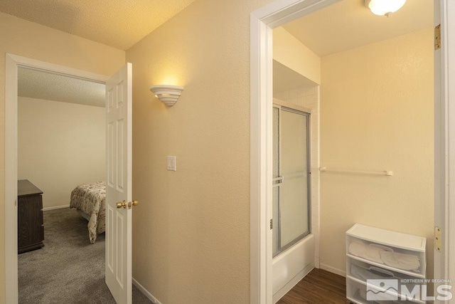 bathroom with a textured ceiling and enclosed tub / shower combo