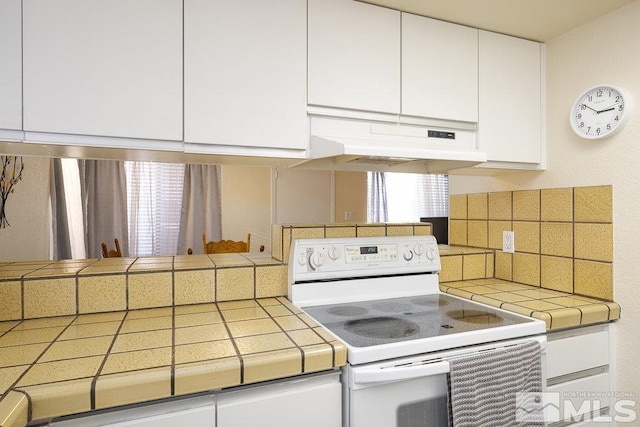 kitchen with white electric range, white cabinets, and tile countertops