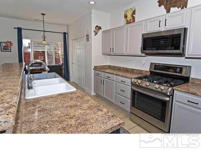 kitchen featuring gray cabinets, appliances with stainless steel finishes, light tile patterned floors, pendant lighting, and sink