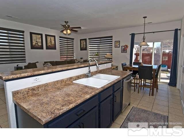 kitchen featuring sink, dishwasher, decorative light fixtures, and a kitchen island with sink